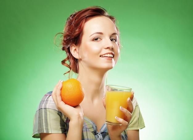 Woman with orange juice over green background