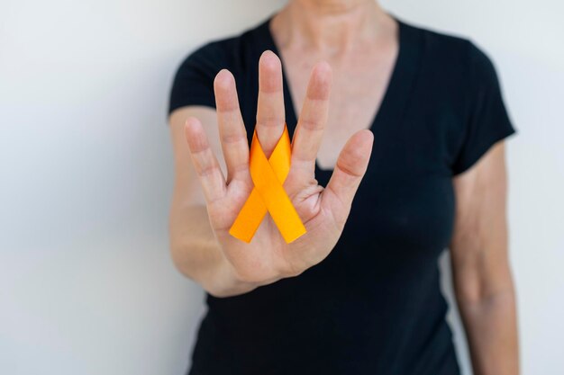 Donna con nastro arancione al dito. campagna per prevenire il cancro della pelle, il melanoma, l'arancia di dicembre