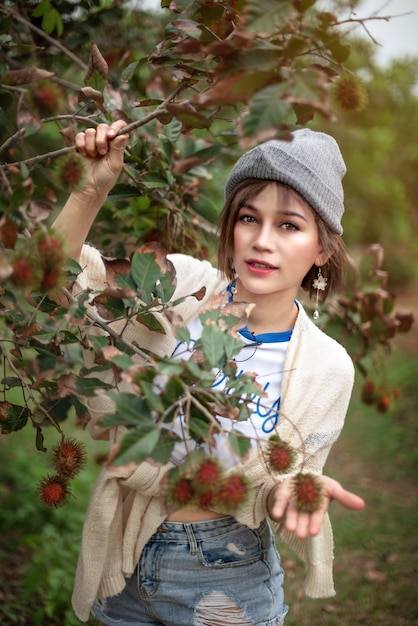 Donna con frutta biologica rambutan nel frutteto