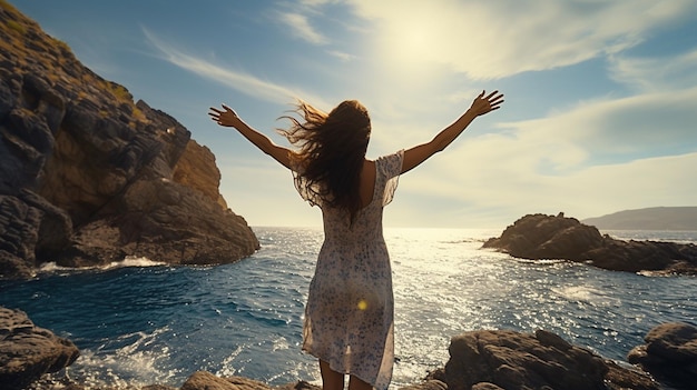 Foto donna con le braccia tese che si gode il vento e respira aria fresca sulla spiaggia rocciosa