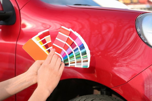 Foto donna con campioni di tavolozza che scelgono il colore per dipingere il primo piano dell'auto