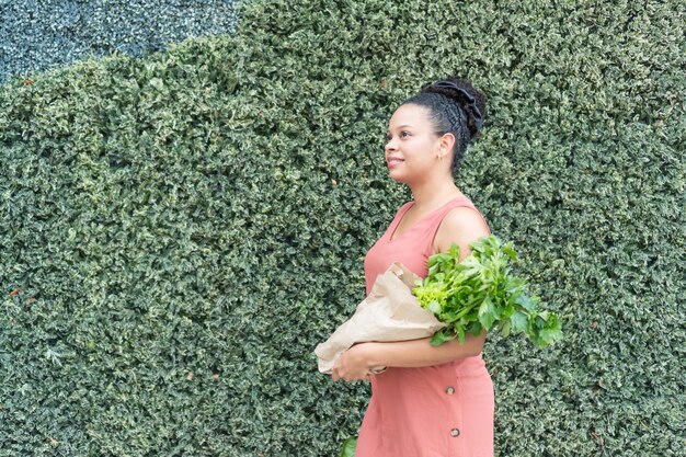 Foto donna con un sacchetto di carta di erbe fresche contro il verde