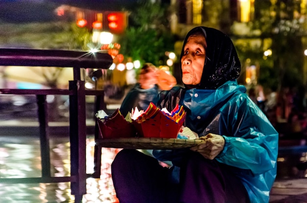 Фото Женщина с бумажными ремеслами сидит в освещенном городе ночью