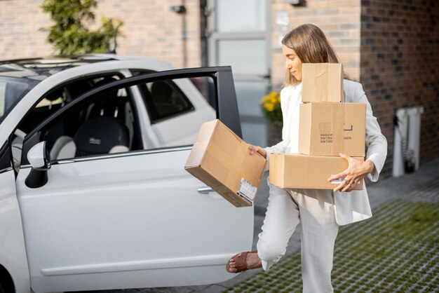 車と家の近くに荷物を持っている女性