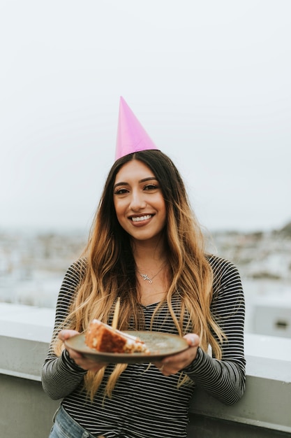 Donna con un cappello di festa festeggia il suo compleanno su un tetto