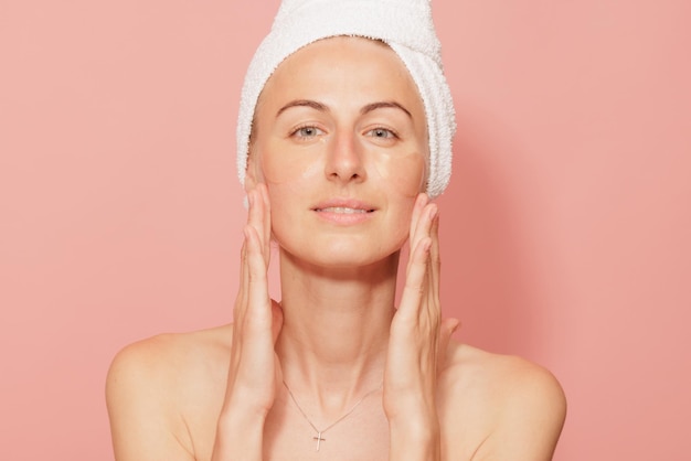 Woman with patches under her eyes touching her smooth skin