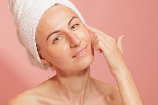 Woman with patches under her eyes touching her smooth skin