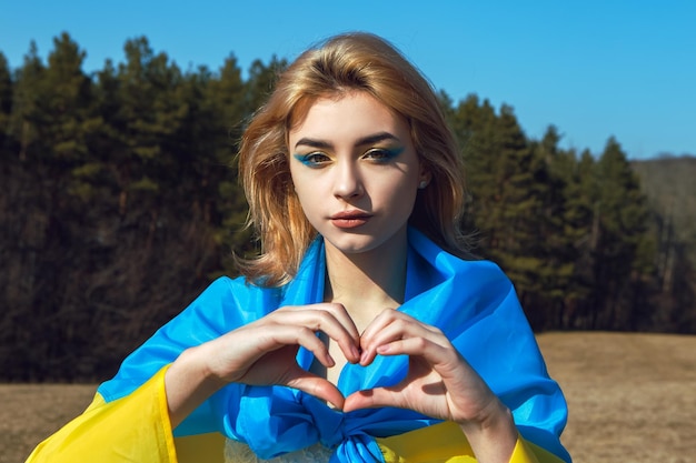 写真 ウクライナの旗に包まれた愛国的な化粧をした女性ウクライナのコンセプトで立つ