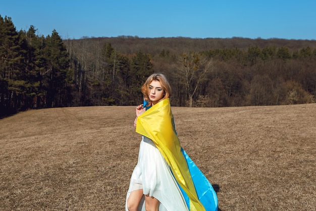 Woman with patriotic makeup wrapped in ukrainian flag Stand with Ukraine concept