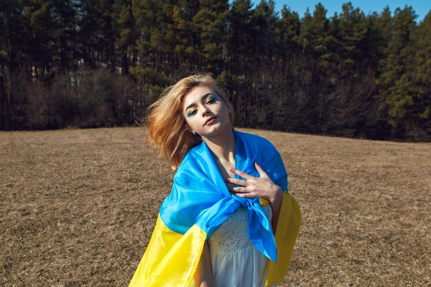 Woman with patriotic makeup wrapped in ukrainian flag Stand with Ukraine concept