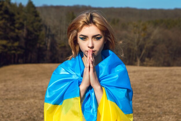 Woman with patriotic makeup wrapped in ukrainian flag Stand with Ukraine concept