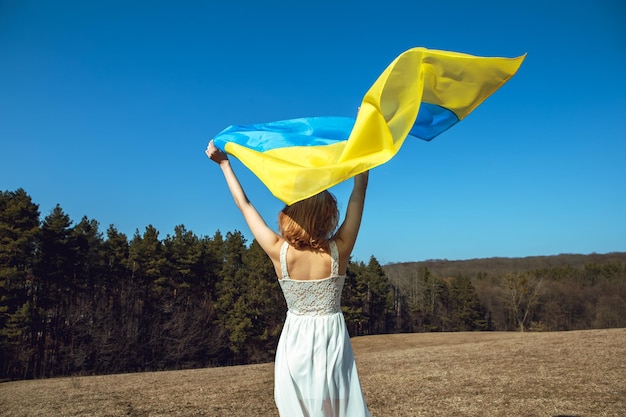 Woman with patriotic makeup wrapped in ukrainian flag Stand with Ukraine concept