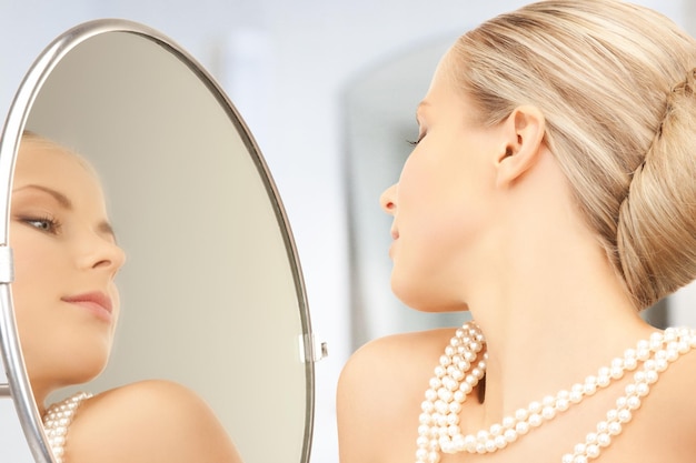 woman with pearl necklace looking in the mirror