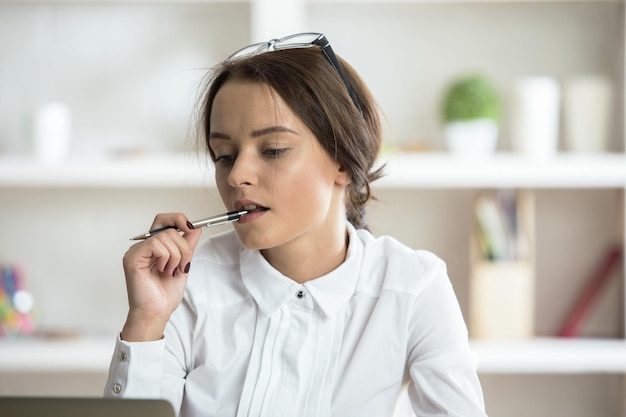 Woman with pen in mouth