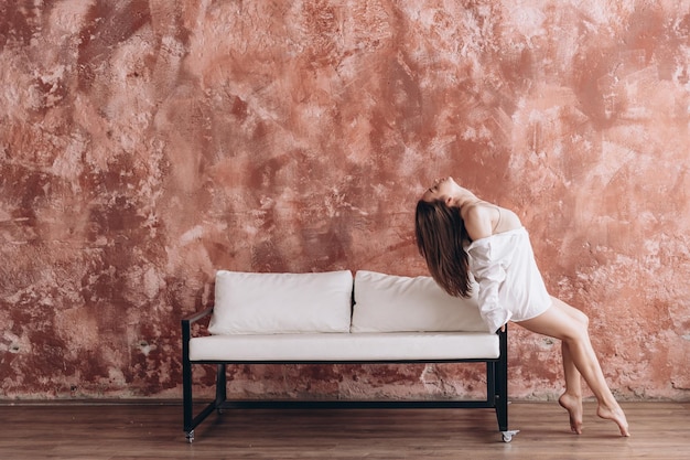 woman with a perfect figure dressed in a bodycolor body posing for a photo near the sofa