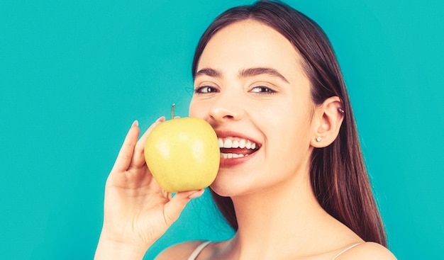 Woman with perfect smile holding apple blue background Woman eat green apple Portrait of young beautiful happy smiling woman with green apples Healthy diet food