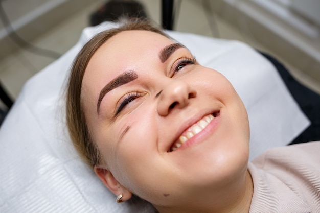 Premium Photo | Woman with permanent makeup tattoo on her eyebrows.  close-up beautician makes makeup applies a foundation. professional make-up  and cosmetic skin care.