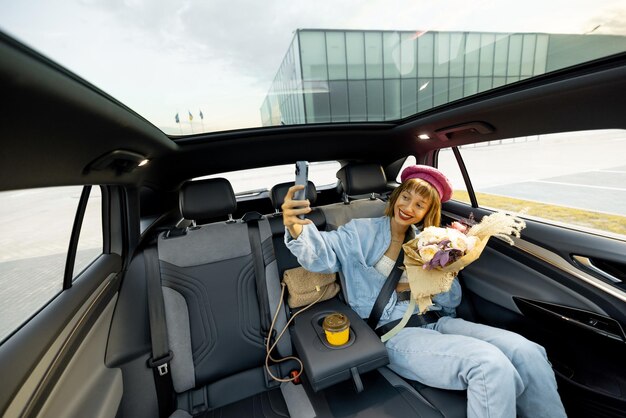 Woman with phone and flowers on backseat of a car