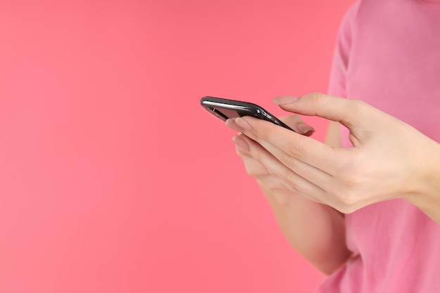 Woman with phone on a pink background, space for text