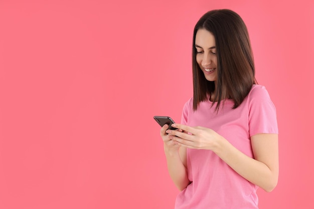 Woman with phone on a pink background, space for text