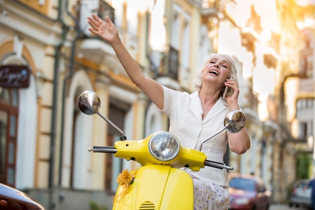 Woman with phone on scooter.