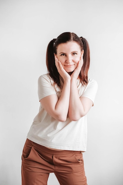 Woman with pigtails and a funny face wearing a T-shirt on a white background. Copy, empty space