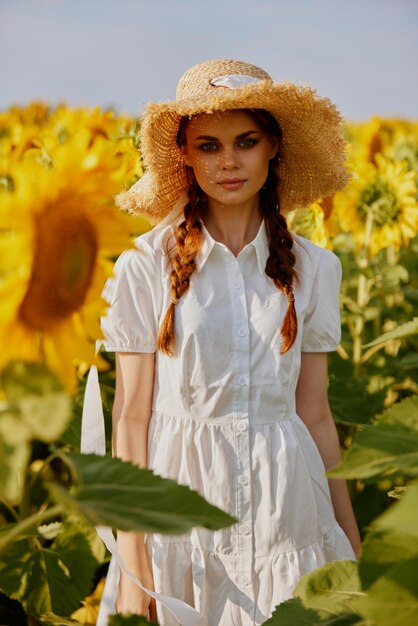 Фото Женщина с косичками в шляпе на поле подсолнухов летом