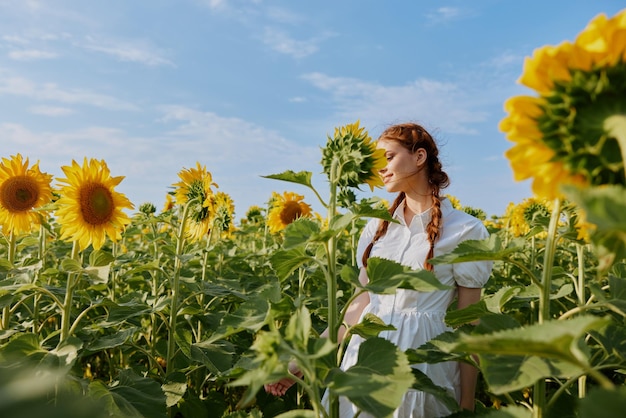 Woman with pigtails in a white dress admires nature flowering plants