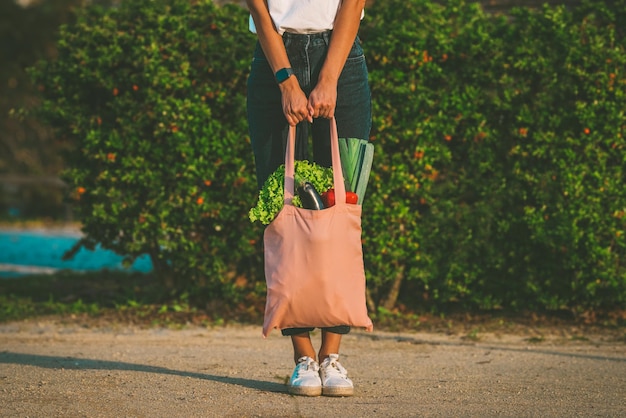 Photo woman with pink cotton reusable eco bag with fresh vegetables zero waste plastic free mockup