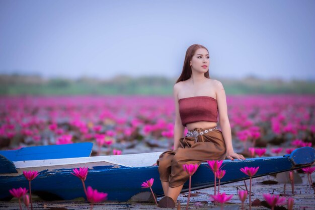 Woman with pink flowers on field against sky