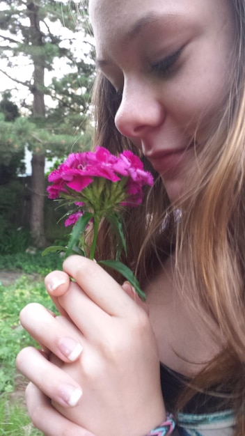 Foto donna con fiori rosa al parco