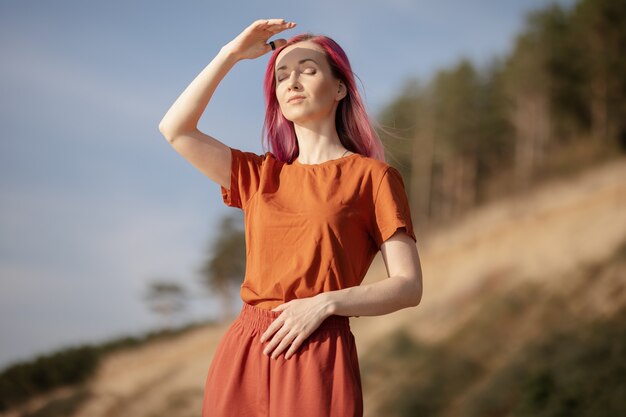 woman with pink hair enjoying the sun and wind on the beach