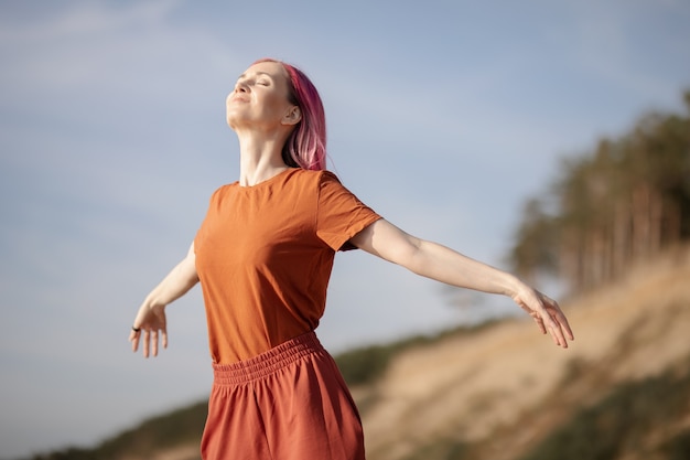 Photo woman with pink hair enjoying the sun and wind on the beach