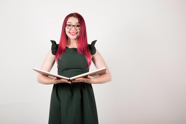 Woman with pink hair on white holding book