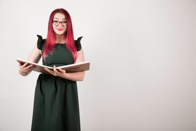 Woman with pink hair on white holding book