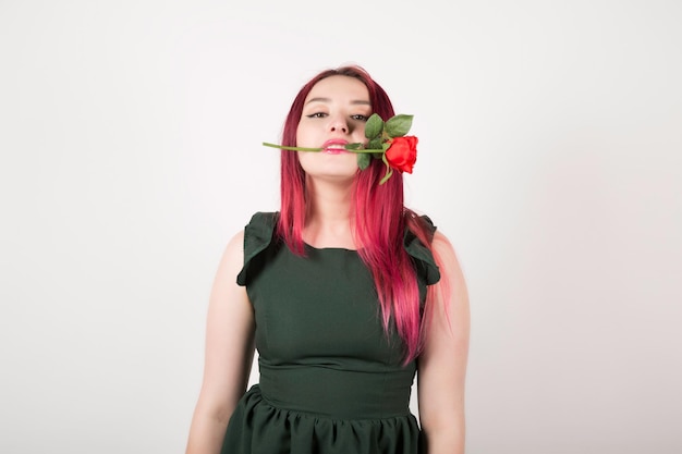 Woman with pink hair on white holding rose