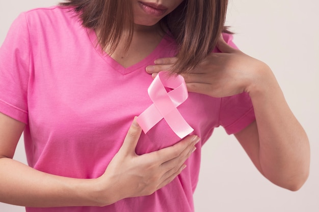 Woman with pink ribbon holding her breast to checking breast cancer.