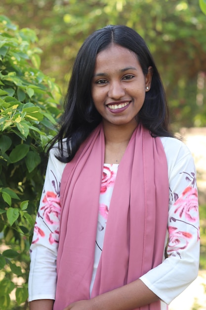 A woman with a pink scarf smiles for the camera.