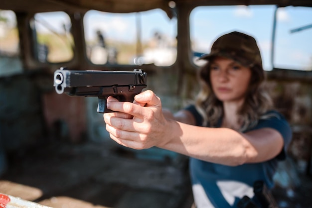 손 에 권총 을 들고 있는 여자 가 사격장 에서 총 을 는 법 을 배우고 있다