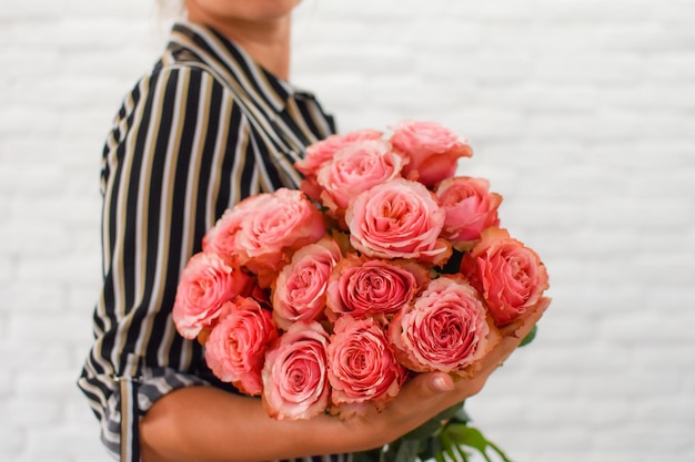 женщина с удовольствием держит в руках букет розовых пионов