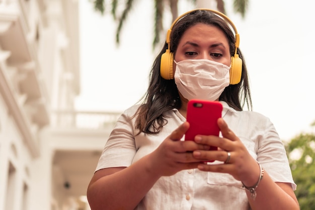 Woman with protective mask in the city listening to music