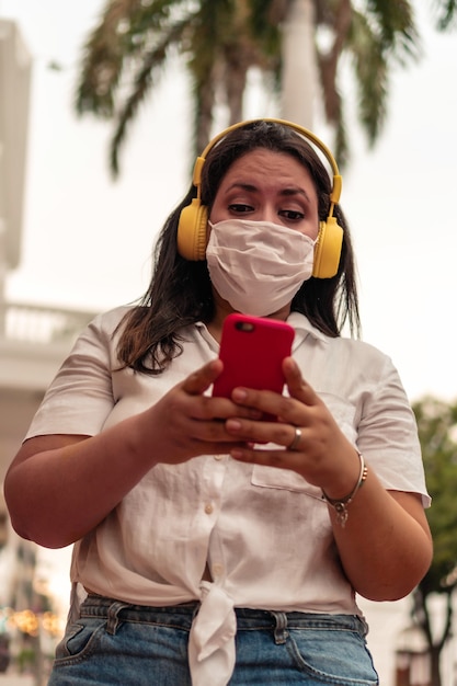 Donna con maschera protettiva in città che ascolta musica