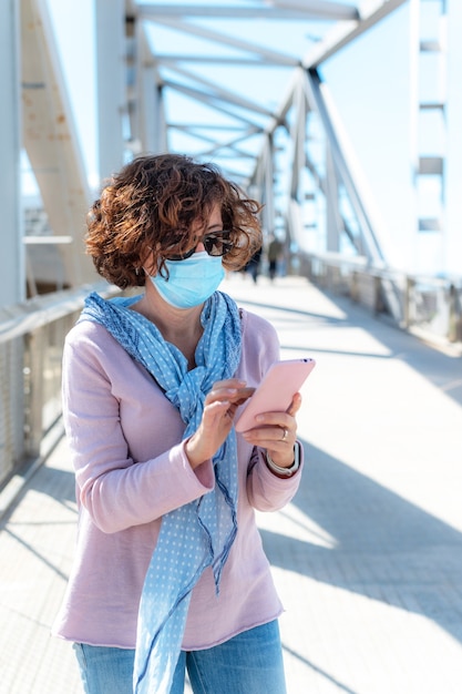 Woman with protective mask looking at the phone