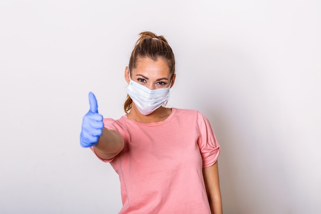 Woman with protective mask showing thumb up, and looking at camera.