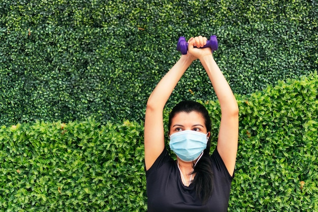 Photo woman with protective mask with dumbbells