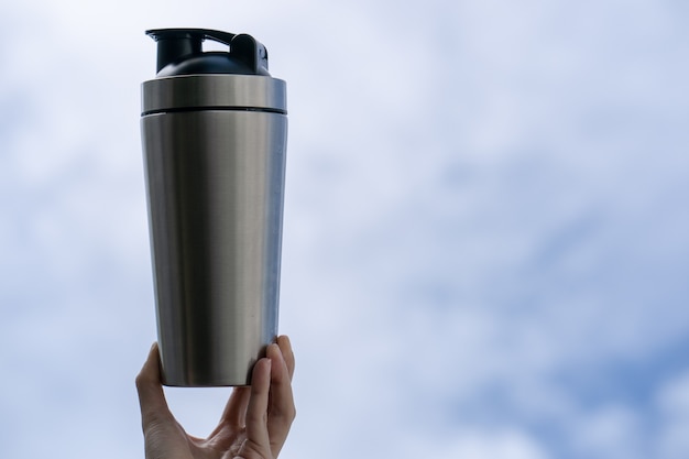 Photo woman with protein drink in shaker in hand over sky