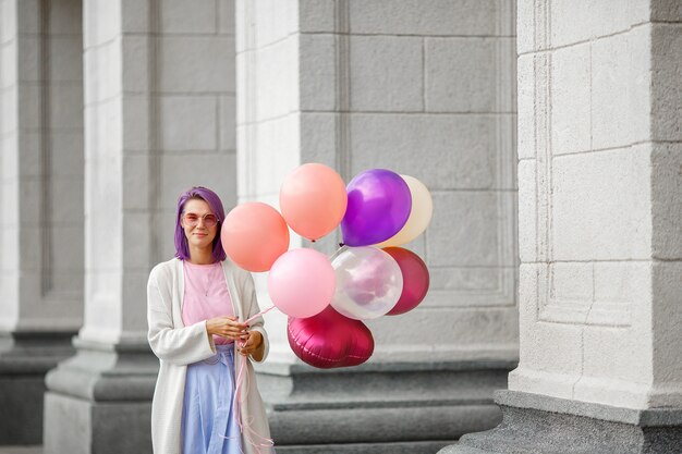 Photo woman with purple hair in pink glasses standing with bunch of airbaloons