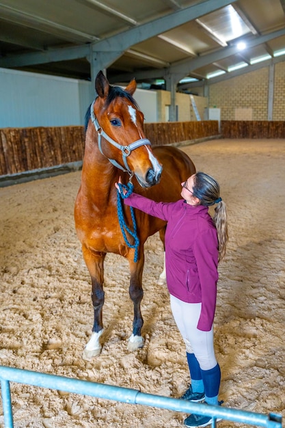 Foto donna con un cavallo da corsa in un'area di allenamento