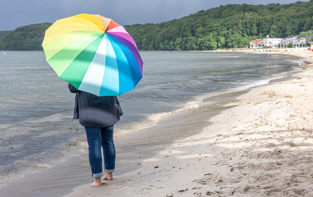 海岸に虹の傘を持った女性