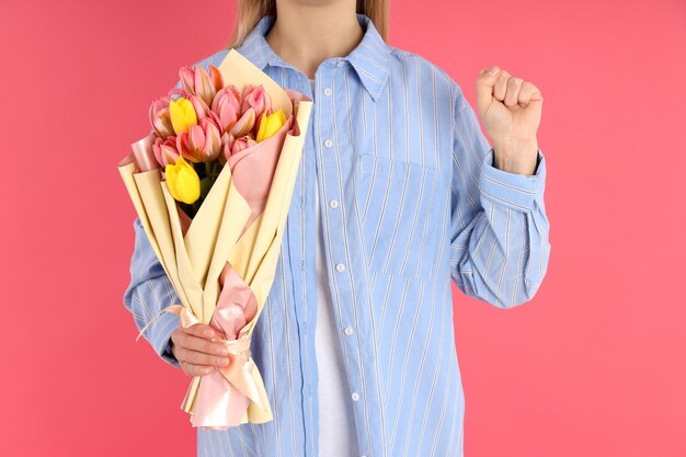 Woman with raised fist holding bouquet on pink background